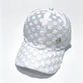 Détail d'une casquette de baseball en dentelle blanche avec badge doré logo M - Blanc Logo Rond M / Adulte, Circonférence du chapeau 58cm réglable