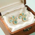 Close-up macro view of vintage green enamel flower earrings in a wooden gift box - Cherry Blossom Style / Blue