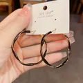 Dettaglio di orecchini a cerchio intrecciati placcati oro con smalto nero - Cerchio Smaltato Nero Intrecciato / Nero
