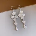 Dettaglio macro di orecchini vintage in argento con motivi floreali e eleganti pendenti a goccia - Argento