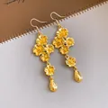 Visuale dettagliata di orecchini pendenti vintage dorati con fiori e ciondoli a goccia. - Oro
