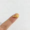 Detailansicht eines kleinen goldenen Wal-Anhängers für DIY-Schmuck auf einer Fingerspitze - Wal Stil (P1-4) / Gold