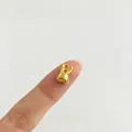 Nahaufnahme eines goldenen Kaninchenanhängers auf einer Fingerspitze zum Größenvergleich - Hase Stil (P1-4) / Gold