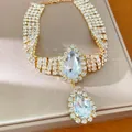 Detailed shot of a luxury gold-tone necklace with blue pear-shaped crystals and rhinestones. - Gold