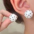 Modern white acrylic round stud earrings featuring black polka dots worn on ear - Polka Dot Hemispherical Studs (DZ-953)