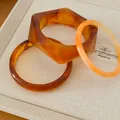 Close-up detail shot of geometric resin bangles in amber and orange marble stone finish. - Three-Piece Set / Brown & Beige (Set Of 3)