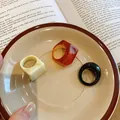 Detail view of three chunky resin rings in amber, black, and cream on a ceramic dish - European Retro Geometric Combo (21#)