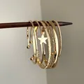Vue macro détaillée de plusieurs bracelets en métal doré avec un charm étoile et des textures - Style 6 / Ensemble de 6 Pièces / Or