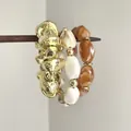 Vue détaillée de bracelets élastiques empilés avec textures métal doré et marbre - 8# Jonc - Marron Kaki / Ensemble trois pièces / Or