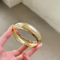 Detalle de un brazalete ancho de acrílico dorado con un acabado metálico de alto brillo - 1# Pulseras - Dorado - Pequeño