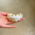 Primer plano detallado de un brazalete de acrílico blanco jaspeado con tachuelas doradas - Brazaletes abiertos 5# - dorado y blanco