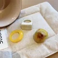 Detailed macro view of three colorful geometric resin rings set on a beige fabric mat. - Sweet Fresh Geometric Style (17#)
