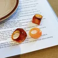 Aesthetic set of chunky amber and orange resin rings displayed on an open magazine - Amber Marbled Geometric Style (24#)