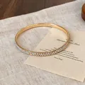 Elegante bracciale rigido dorato con doppie file di cristalli iridescenti lucidi. - Strass AB / Oro