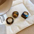Detailed macro shot of three geometric brown resin rings with shimmering textures on a white pouch - Retro Gold Powder Marbled Style (20#)