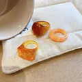 Detailed macro view of three resin geometric rings in amber and orange tones on beige fabric - Amber Marbled Style (19#)