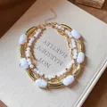 Detailed view of multilayer white marble acrylic bead and gold tube necklace. - White / Gold
