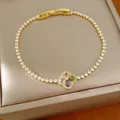 Detail van een gouden klaverarmband met gekleurde zirkoonstenen op een displaydoos - Goud Veelkleurig