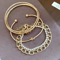 Primo piano di un set di 4 braccialetti d'oro con strass, catene e nodi - Oro