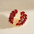Detail view of elegant red marquise crystal feather wing earrings with gold setting. - Stud Pin Style / Red