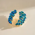 Close-up macro view of vibrant blue and green marquise crystals on gold feather earrings. - Stud Pin Style / Green