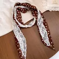 Detail van bruine polkadot sjaalketting met wit kant en een parel - Stippen / koffiekleur