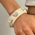 Detailed view of a wide resin bangle with seashell and pearl embellishments on wrist - White (1493)
