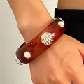 Close-up of retro tortoiseshell resin bangle with golden shell and pearl details - Amber (9538)