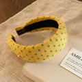 Vue détaillée d'un serre-tête rembourré vintage jaune à pois verts sur un livre - Jaune