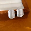 Gros plan de boucles d'oreilles minimalistes en argent texturé en forme de C dans l'écrin - Argent