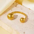 Gros plan d'une bague ouverte en acier inoxydable doré avec embouts sphériques polis - Style Boule Ronde Dorée