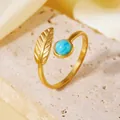 Gros plan sur une bague feuille en acier inoxydable doré avec une pierre turquoise. - Style Feuille d'Or
