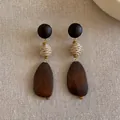 Macro detail of retro geometric wood earrings featuring woven straw bead and dark finish - Style 1 / Brown