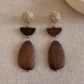 Close-up of bohemian geometric drop earrings with woven balls and wooden pendants - Style 2 / Brown