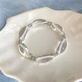 Detalle de una pulsera de resina transparente con líneas blancas y adornos azules. - Blanco-Azul