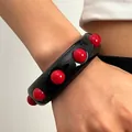 Close-up of retro chunky black acrylic wide bangle with large red spherical studs - Black With Gold Beads (7779)