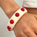 Detail view of retro cream acrylic wide bangle with bold red dot accents - White With Red Dots (7976)