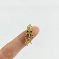 Detailansicht eines Mini-Gold-Oktopus-Anhängers mit funkelnden blauen Steinen auf einem Finger - Oktopus (Blauer Strass)