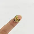 Nahaufnahme eines goldenen Oktopus-Anhängers mit schwarzen Strasssteinen am Finger - Tintenfisch (Blauer Strass)