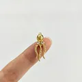 Detailansicht eines winzigen goldenen Krakenanhängers mit glitzernden Strasssteinen am Finger. - Oktopus (Rosa Strass)