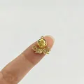 Detaillierte Makroansicht eines goldenen Krakenanhängers mit Zirkonia auf einem Finger - Tintenfisch (Rosa Strass)