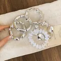 Vista dettagliata delle trame metalliche del set di braccialetti di perle acriliche. - Five-Piece Set / Argento