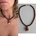Detailweergave van een bruine kralenketting met natuurlijke schelphanger voor de strandstijl. - Abacus Kraal Bruine Wulk Ketting / 38+5cm / Bruin