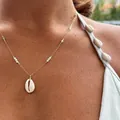 Primo piano di collana con conchiglia ciprea con catena dorata e perle blu dettagli - Collana con Conchiglia e Catena in Perle d'Acqua Dolce