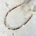 Dettaglio di una collana da spiaggia con conchiglie bianche e perline nei toni della terra. - Collana di Perline Mini Conchiglia - Marrone Beige
