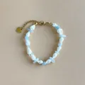 Vista dettagliata di un braccialetto da spiaggia con conchiglie bianche e pietre blu. - Bracciale con Conchiglia e Scaglie di Pietra