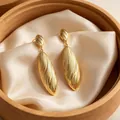 Elegant textured gold oval dangle earrings with a ribbed pattern on cream silk cloth - Oversized Waterdrop