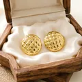 Detail view of gold stainless steel round earrings with quilted texture in a box - Round Checkered Pattern