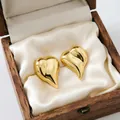 Close-up of elegant gold heart-shaped earrings inside a vintage wooden jewelry box - Concave Heart