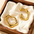 Detailed view of chunky gold-colored irregular metal hoop earrings in a wooden box - Irregular Lines